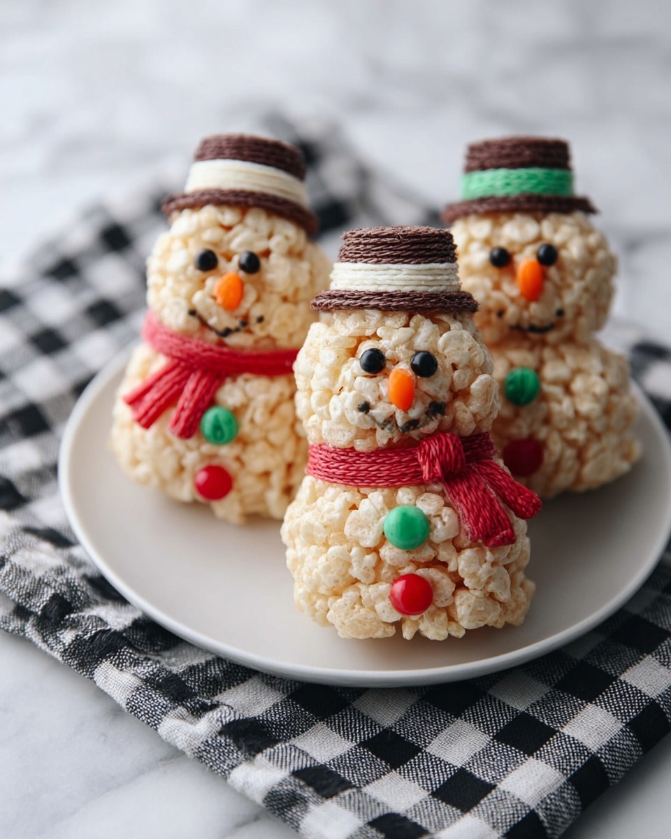 The image shows three snowman-shaped treats made of light beige puffed rice cereal, each with two round layers stacked to form the body and head. Each snowman has black eyes and a small orange nose made from small candies, a red candy scarf wrapped around the neck, and colorful green and red candy buttons on the body. Each snowman wears a small top hat made of a round chocolate base and a white cylindrical top with a green band. They are placed on a white plate resting on a black and white checkered cloth, all set on a white marbled surface. photo taken with an iphone --ar 4:5 --v 7