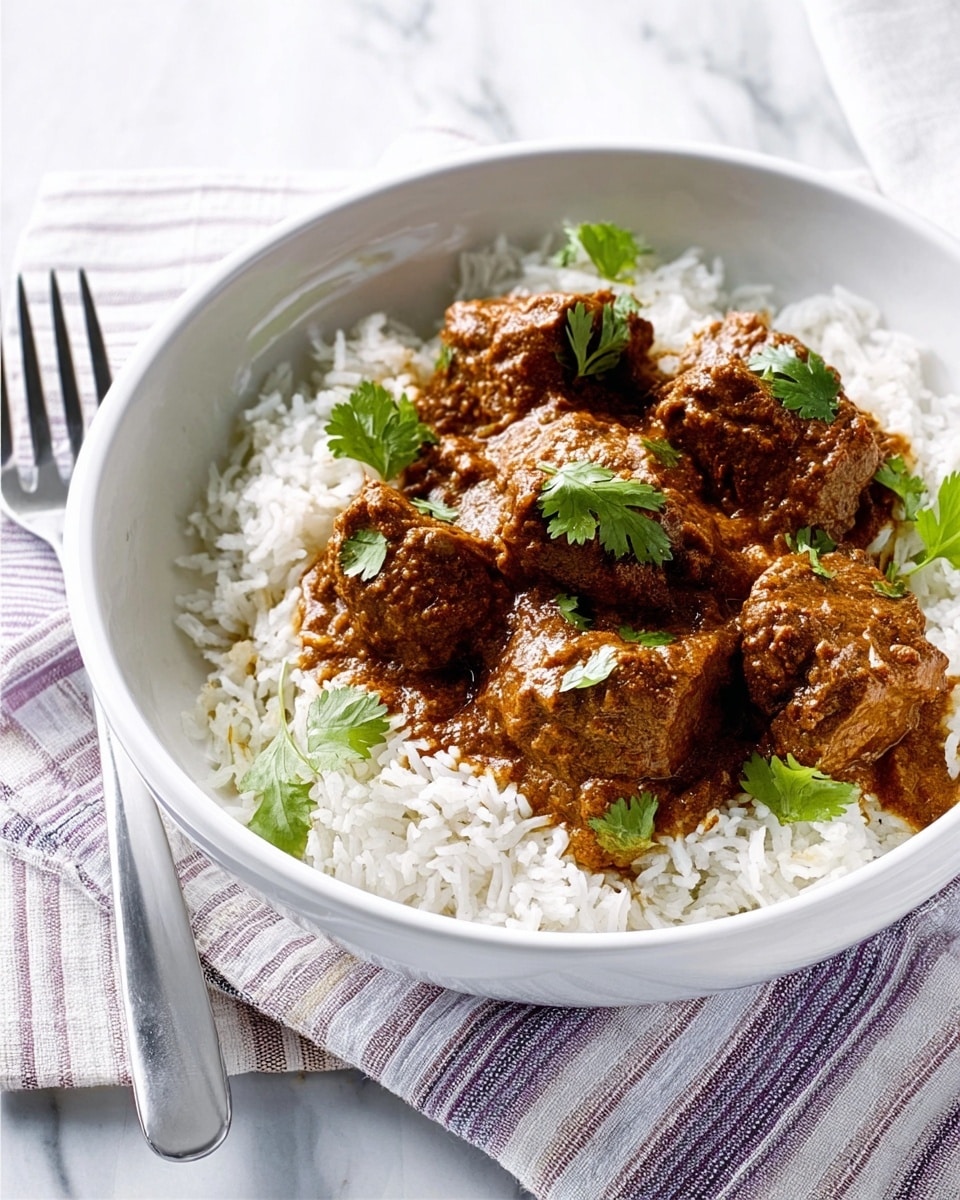 A white bowl filled with a base layer of fluffy white rice, topped with four pieces of brown, thick curry-covered meat garnished with small green cilantro leaves; the bowl sits on a white marbled surface with a folded striped cloth underneath, and a silver fork rests beside the bowl. Photo taken with an iphone --ar 4:5 --v 7