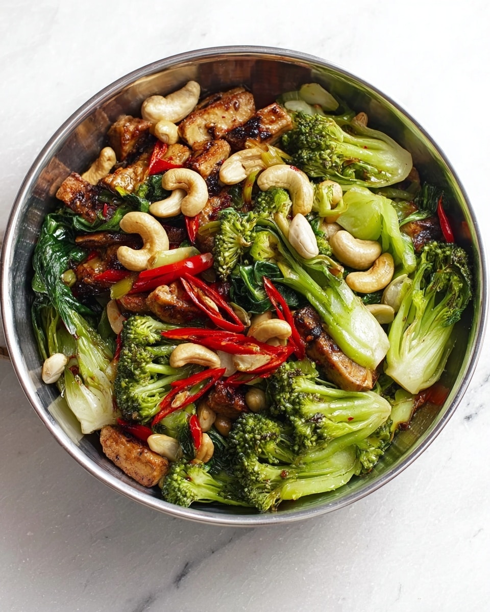 The image shows a white bowl filled with a colorful vegetable stir-fry on a white marbled surface. The dish has three main layers: the base layer features bright green broccoli florets and bok choy with light green and white stalks, some with slight charring. On top of that, lightly browned pieces of tofu or chicken are mixed in, giving a textured, slightly crispy look. Scattered across are pale cashew nuts and thin slices of red chili, adding pops of white and red. The vegetables and nuts create a vibrant, fresh, and healthy appearance. Photo taken with an iphone --ar 4:5 --v 7