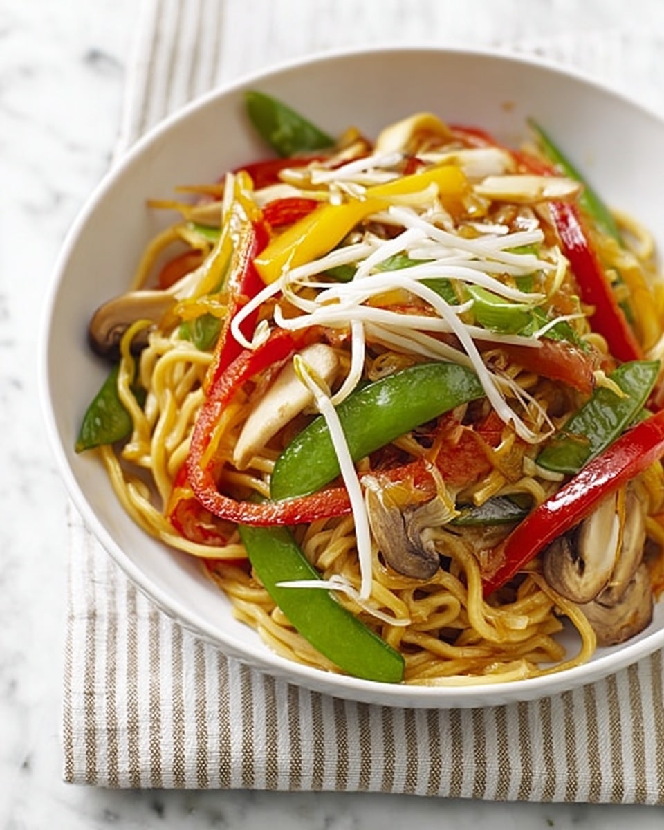 A white bowl filled with stir-fried noodles and colorful vegetables sits on a striped cloth over a white marbled surface. The dish has thick, yellow noodles forming the base layer, topped with bright red and yellow bell pepper strips, green snap peas, and fresh bean sprouts scattered on top. There are also visible slices of mushrooms and green onions mixed among the noodles. The colors are vibrant, showing a mix of fresh vegetables and glossy cooked noodles. The photo has a bright, natural light. Photo taken with an iphone --ar 4:5 --v 7