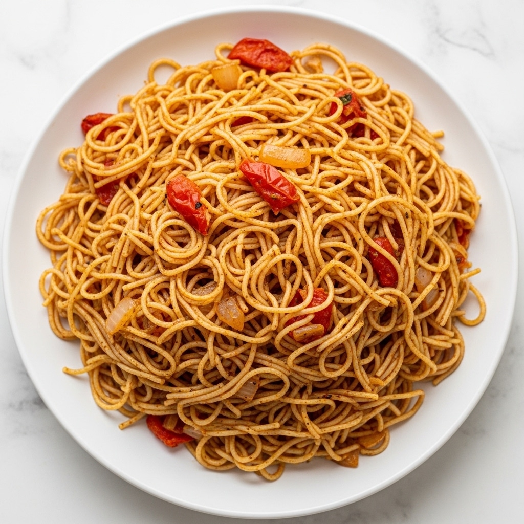 A white bowl filled with a large mound of cooked spaghetti noodles mixed with small pieces of diced tomatoes and onions, all coated in a light reddish sauce speckled with black pepper and spices, giving the noodles a slightly glossy and textured look. The noodles form irregular layers with some strands overlapping, showing bits of softened vegetables throughout. The bowl sits on a white marbled surface. photo taken with an iphone --ar 4:5 --v 7