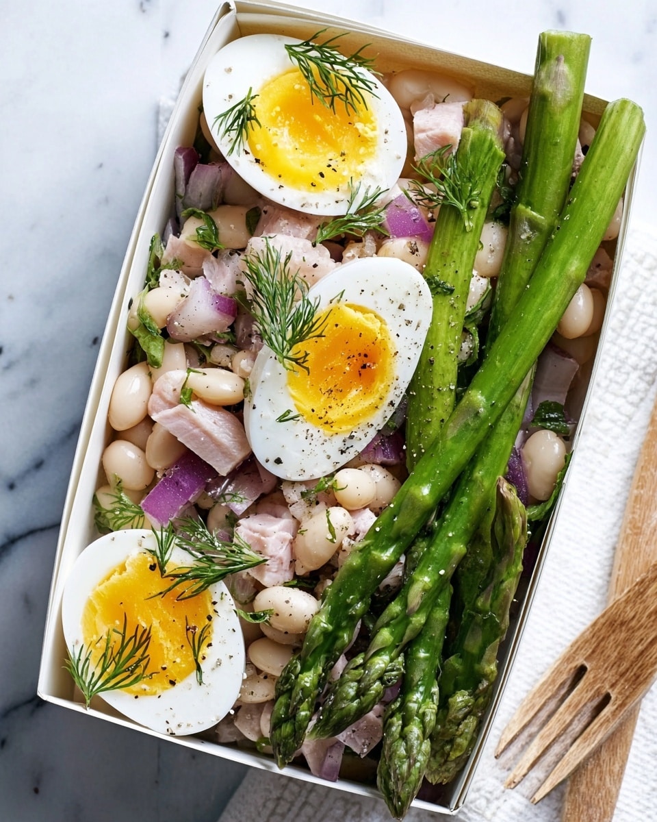 A white rectangular box is filled with a fresh salad composed of three wedges of a soft-boiled egg with a runny yellow yolk on top, bright green asparagus spears on the side, and a mix of white beans, chopped red onion, and small pieces of light brown chicken scattered underneath. The salad is lightly sprinkled with small green dill sprigs and black pepper. The box sits on a white marbled surface with part of a white wooden texture visible on the side. photo taken with an iphone --ar 4:5 --v 7