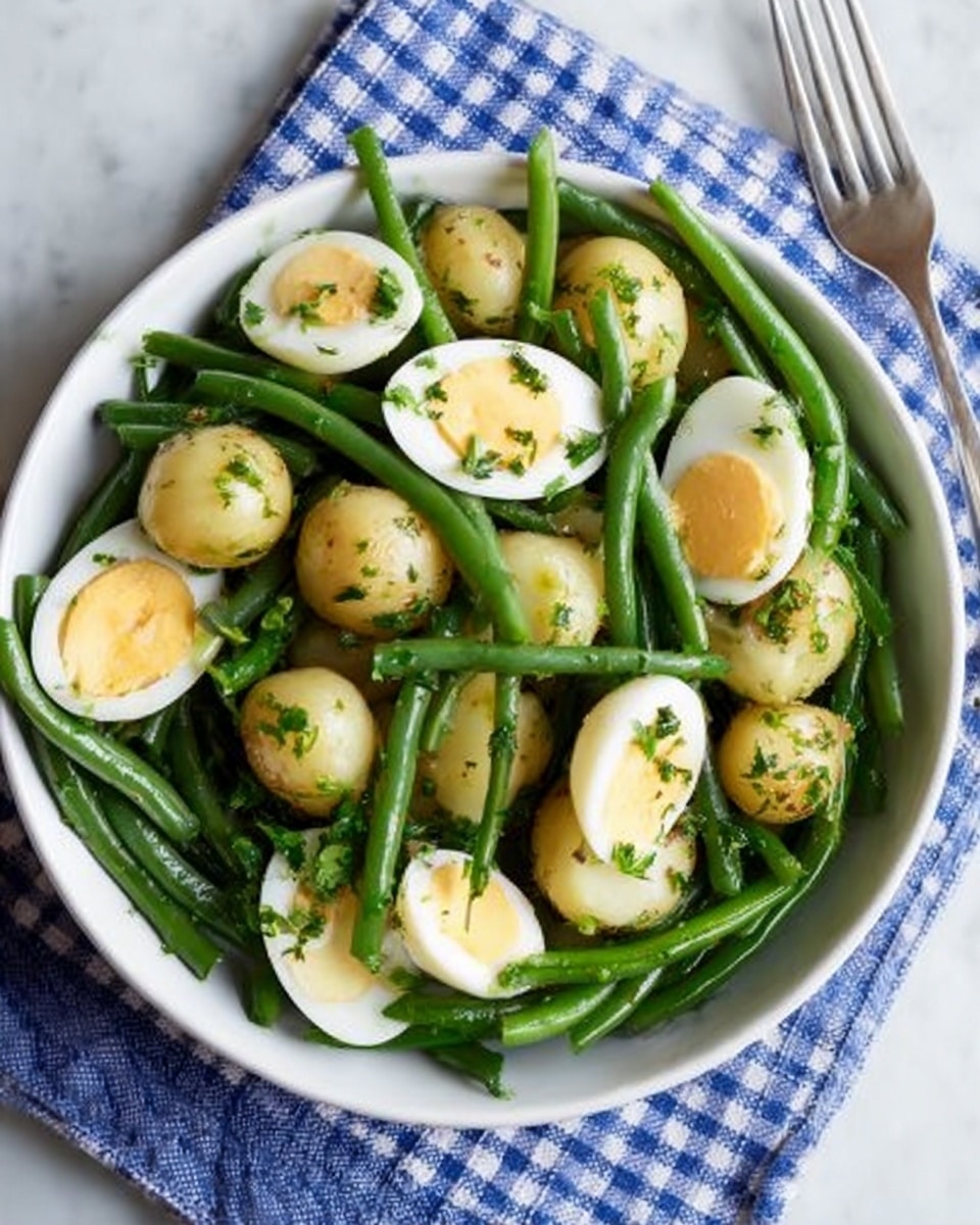 A white bowl filled with a mix of green beans and small round potatoes, both lightly coated with herbs, placed on a blue and white checkered cloth over a white marbled surface. On top of the green beans and potatoes, there are several slices of halved boiled eggs with bright yellow yolks and smooth white edges scattered evenly. A silver fork is positioned to the right side of the bowl. The textures show the firm smoothness of the potatoes, the crispness of the green beans, and the soft boiled eggs. photo taken with an iphone --ar 4:5 --v 7