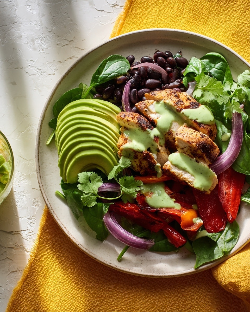 A white plate sits on a white marbled surface with a yellow cloth to the side, holding a colorful salad. The base layer is fresh green spinach leaves topped with slices of grilled red bell pepper and scattered black beans. On top of those, thinly sliced rings of purple onion add texture. Four pieces of golden-brown grilled chicken rest over the salad, with patches of light green creamy dressing drizzled across them. A fanned-out sliced avocado with its smooth light green flesh is placed beside the chicken. Small fresh cilantro leaves are scattered over the top for a fresh touch. In the lower right corner, a small white bowl contains more of the green dressing with a spoon in it. photo taken with an iphone --ar 4:5 --v 7