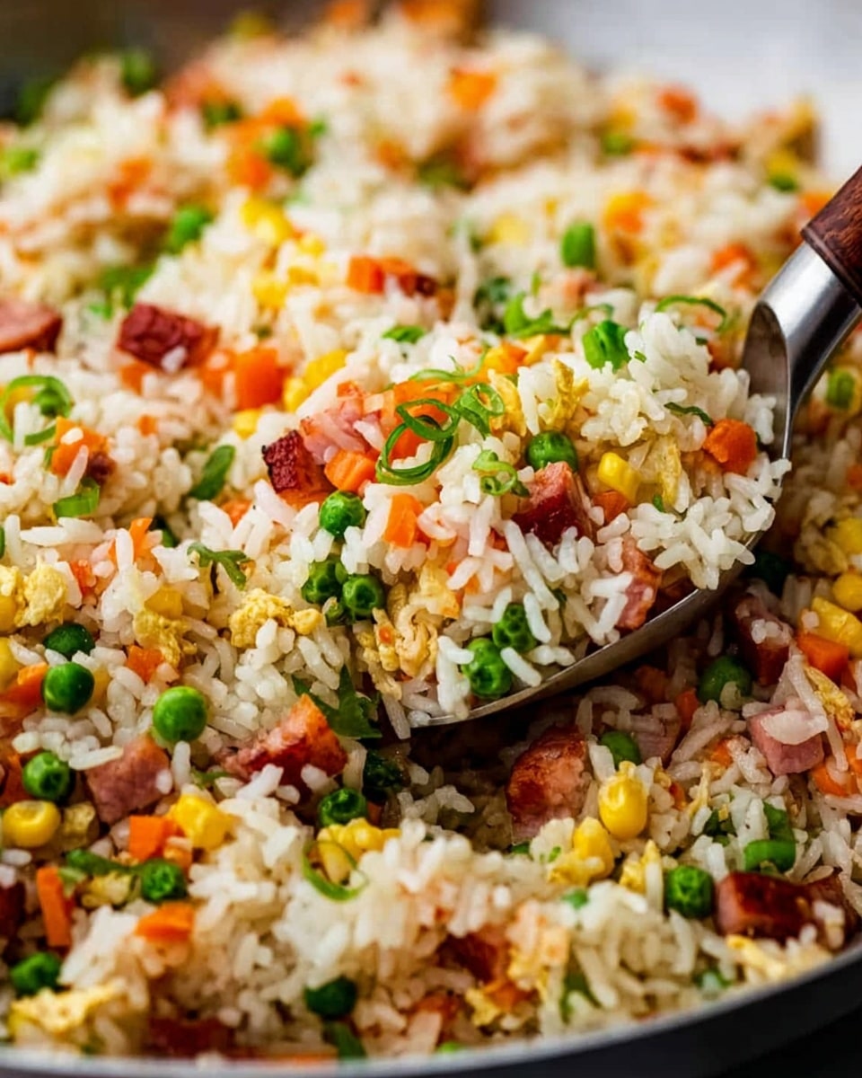 The dish is a close-up view of fried rice in a pan, showing three main layers: the base layer is white fluffy rice grains, mixed evenly throughout with small, colorful diced vegetables such as green peas, orange carrots, and yellow corn, creating a vibrant texture. Scattered within the rice and vegetables are small pieces of browned ham or bacon that add a reddish-brown contrast. On top, finely chopped green onions add a fresh green color and a slightly crunchy texture. A silver spoon with a wooden handle is scooping some of the fried rice, positioned on the right side of the image. The background is a white marbled texture. photo taken with an iphone --ar 4:5 --v 7