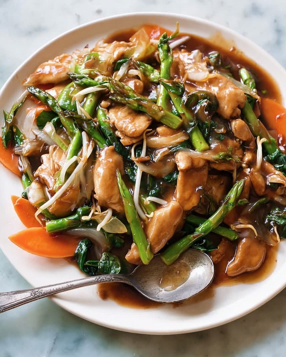 The dish shows a close-up of a stir-fry on a white plate with a glossy brown sauce covering the layers. The bottom layer has wide, thin slices of orange carrot and some green asparagus pieces. On top of that lie light brown, tender chicken pieces with some grilled marks and white bean sprouts scattered around. Bright green leafy vegetables and asparagus tips are mixed evenly throughout the dish. The sauce is thick and shiny, giving the whole meal a moist and delicious look. A shiny metal spoon is partially resting on the right side of the plate, slightly covered by the sauce. The plate is set on a white marbled texture. photo taken with an iphone --ar 4:5 --v 7